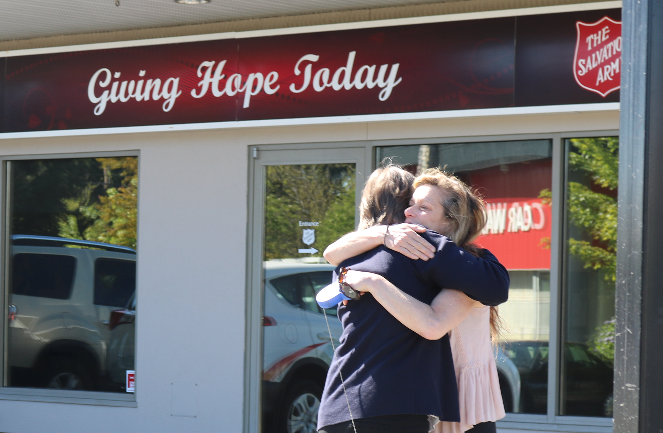 A supportive embrace between two people outside the Salvation Army Comox Valley Ministries building.