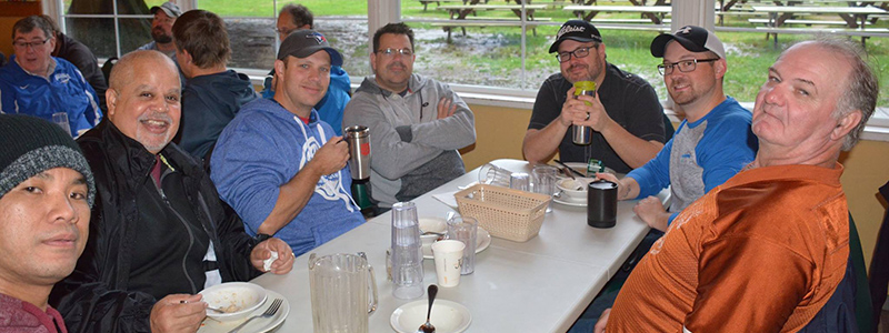 Men from the church sitting together at a table, sharing a meal and conversation during a men’s fellowship gathering.