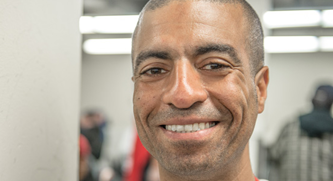 Portrait of a smiling man indoors, with a softly blurred background.
