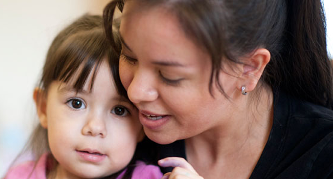 Mother gently holding a young child, showing care, comfort, and support.