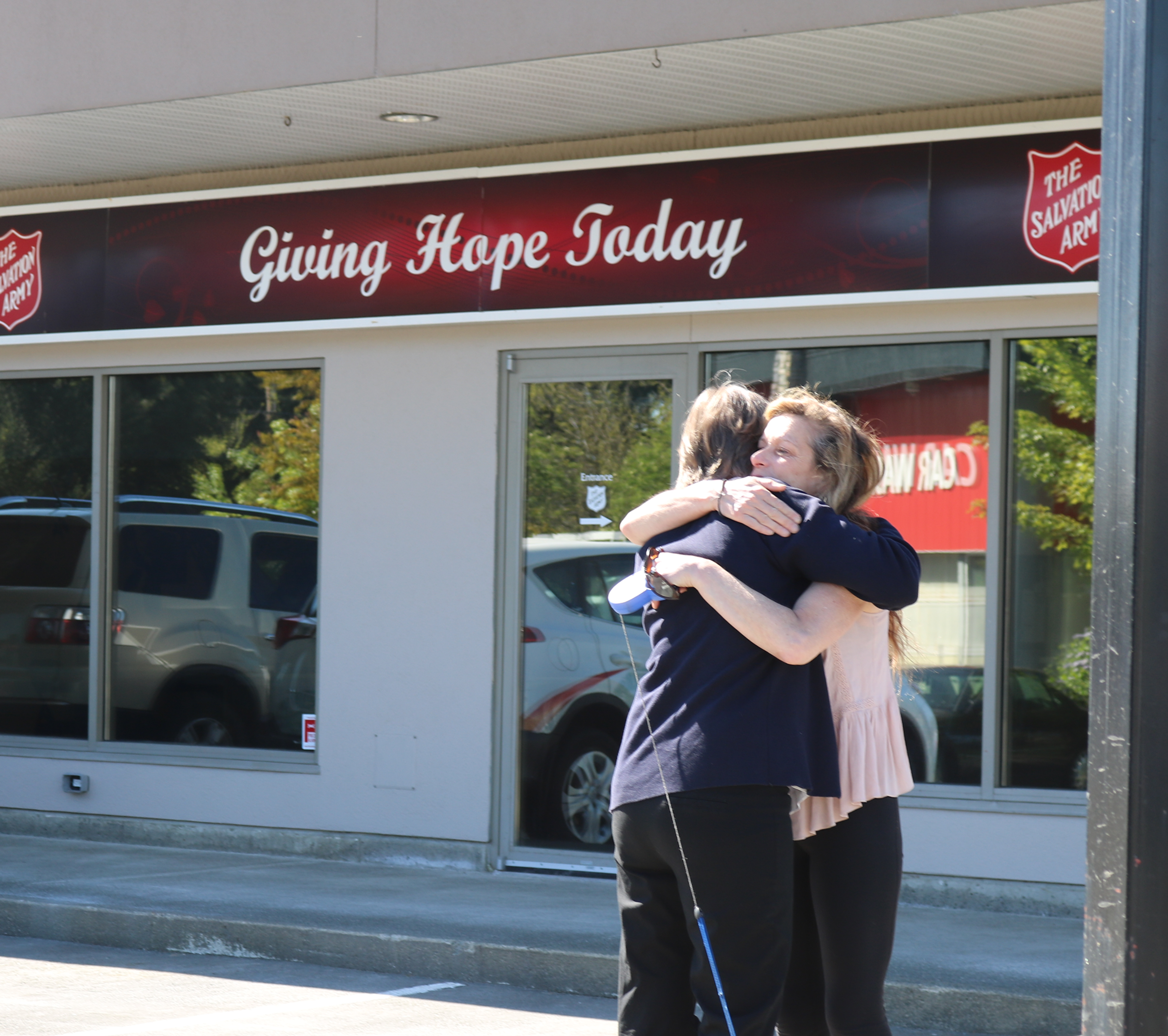 A supportive embrace between two people outside the Salvation Army Comox Valley Ministries building.