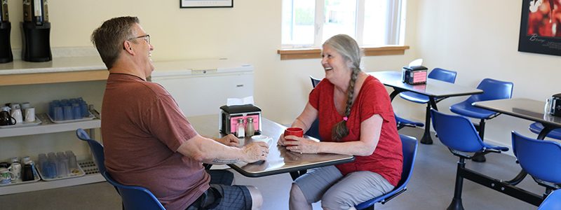 The Salvation Army staff member meeting with a community member at a table in a community room, discussing support and family services in a welcoming environment.